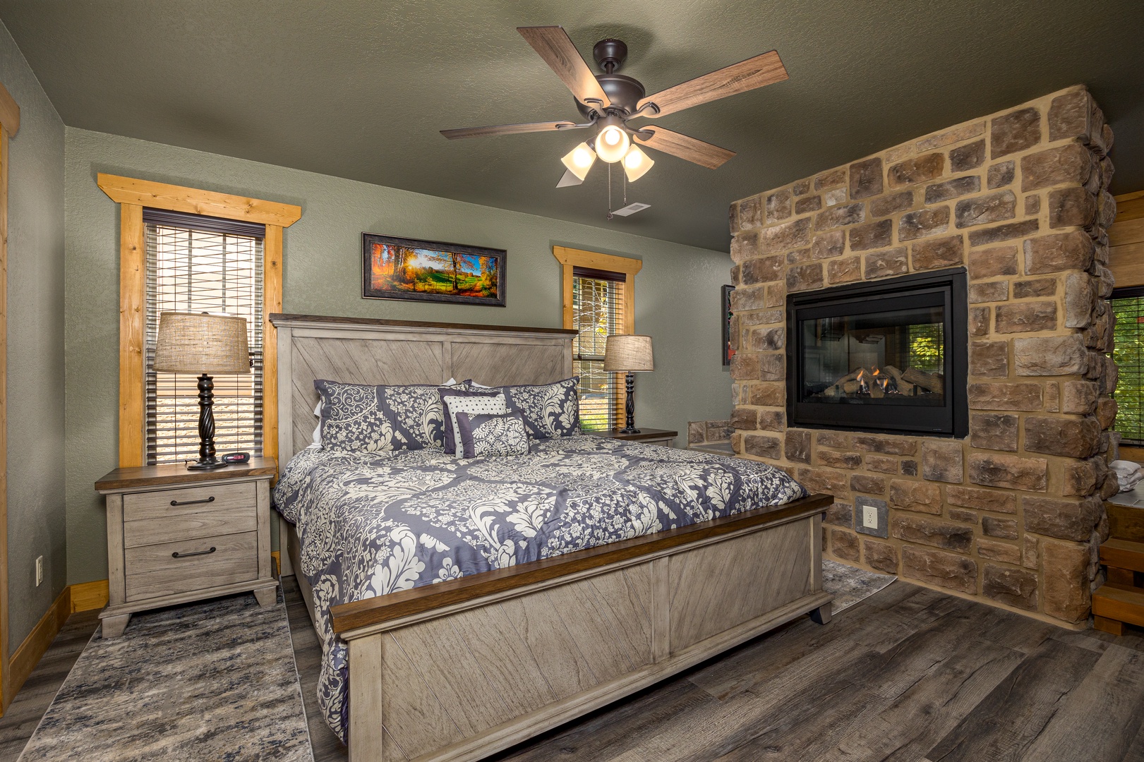Southern Comfort master bedroom, king bed, stone gas fireplace, hardwood floors, and cedar trim at Laurel Estates at The Glades