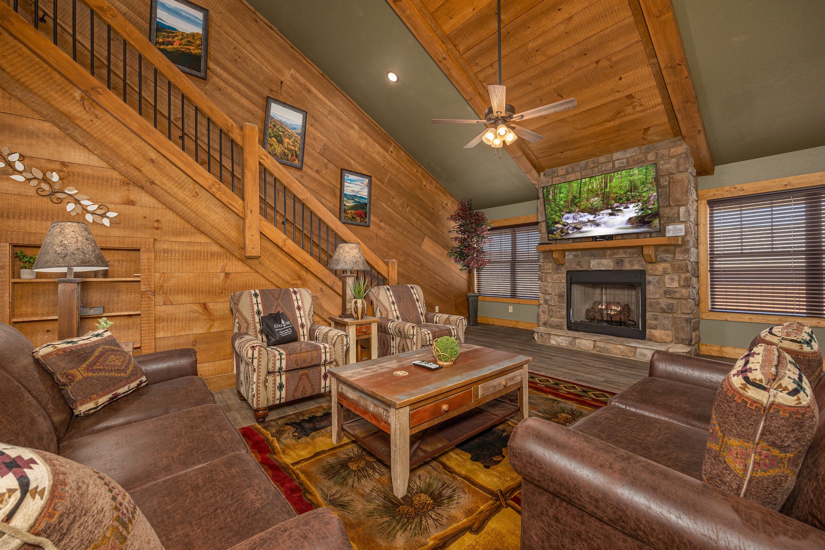 Heaps of Fun cabin living room, vaulted cedar ceiling, stone gas fireplace, rustic leather seating, and mountain-themed decor at Laurel Estates